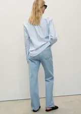 Pantalón de jean celeste de corte recto, tiro medio, con cinco bolsillos y cierre frontal con cremallera y botón.