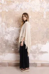 Capa color crudo tejida en algodón, lino y lurex, con flecos en el borde inferior.