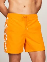 Short de baño naranja con estampado de monogramas TH en blanco a lo largo de la pierna.