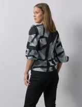 Blusa de gasa estampada con flores verdes sobre fondo blanco, de la marca Sioni. Tiene mangas cortas amplias con abertura y botón.