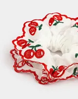 Maxi scrunchie blanco con bordado de cerezas rojas y borde festoneado rojo.