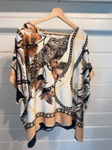 Blusa de satén con estampado de cadenas y hojas en tonos blanco, marrón y negro. Tiene corte amplio, mangas cortas y cuello redondo. Se ajusta a la cintura con un cinturón elástico negro con hebilla dorada.