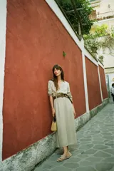 Vestido camisero midi color verde claro, con cuello solapa, escote pico, manga larga remangada con trabilla y botón, bolsillos delanteros de plastrón, cintura elástica, cierre frontal con botones y cinturón de rafia trenzada con hebilla redonda.