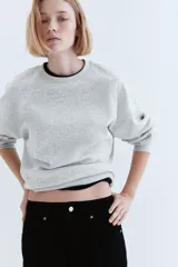 Buzo gris de corte amplio, con cuello redondo y mangas largas.