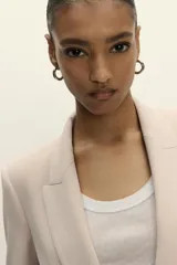 Blazer blanco con cuello solapa y hombreras. Manga por debajo del codo acabada en vuelta con trabilla y botón dorado. Bolsillos delanteros con solapa.