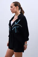 Camisa negra de corte amplio con botones y estampado de líneas con lentejuelas en color celeste y plateado.