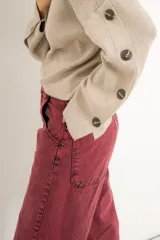 Sweater tejido de punto medio color beige, holgado y cómodo, con cuello redondo y mangas largas con detalle de botones.