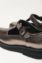 Zapato guillermina color bronce con acabado charol, suela de goma negra y plataforma.
