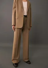 Pantalón de vestir color beige, de corte wide leg, con trabillas, tejido fluido, detalle de pinzas, dos bolsillos laterales y cierre oculto de botón, gancho y cremallera.