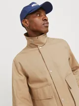 Campera color beige estilo workwear con cuello de pana marrón, cierre frontal con botones a presión, mangas largas y bolsillos frontales con solapa.