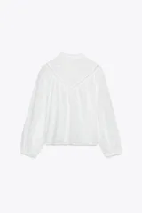 Camisa blanca de manga larga con cuello con volantes y bordados perforados. Cierre frontal con botones a tono.