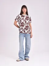 Remera estampada con motivos florales en tonos naranja, beige, gris y rosa.