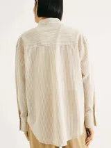 Camisa de manga larga con rayas verticales color naranja y blanco, con cuello camisero y cierre con botones.