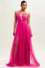 Vestido largo de fiesta color fucsia, con escote halter, espalda descubierta y tajo alto en la pierna.