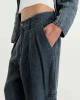 Pantalón de lino color gris gastado, con pinzas, silueta comba en piernas, bolsillos ojal en pierna izquierda y espalda. Largo hasta los tobillos y tiro medio.