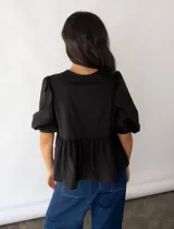Blusa negra de popelina de algodón con corte peplum, mangas abullonadas y lazo en el cuello.