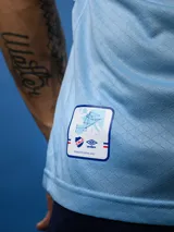Camiseta de fútbol celeste con cuello y mangas con detalles en azul y rojo. Incluye logo de Umbro, escudo del Club Nacional de Football y sponsor Antel.