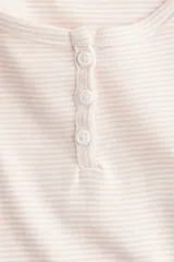 Remera corta de punto acanalado color rosa pálido con rayas horizontales y escote redondo amplio con tapeta de botones.