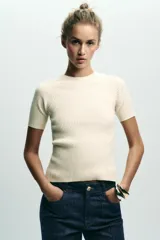Top color crema de punto canalé con cuello redondo y manga corta. Espalda descubierta con lazo combinado en popelín.