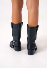 Bota de cuero marrón oscuro con caña media, estribo desmontable y hebilla metálica. Taco de madera de 5cm y suela de caucho.