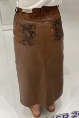 Pollera larga de cuero ovino color marrón, estilo jean, con tajo frontal.