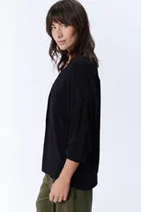 Blusa negra de manga larga con escote en V y cierre frontal con botones.