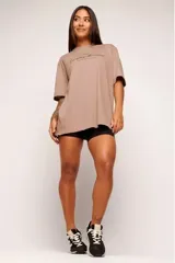 Remera color beige con estampado de texto en el frente, corte amplio y mangas cortas.