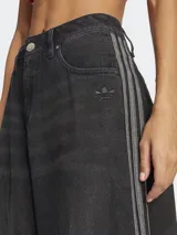 Pantalón de jean negro de corte ancho con tres tiras verticales grises a lo largo de cada pierna y logo de Adidas bordado en el bolsillo delantero.