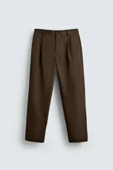 Pantalón relaxed fit color marrón confeccionado en tejido de algodón con estructura twill. Cintura con pliegues frontales, bolsillos laterales en cadera y detalle de bolsillos traseros de doble vivo con botón. Cierre frontal con cremallera y botón.