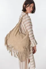 Bolso bandolera de gamuza color beige con flecos largos en la parte inferior.