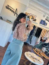 Pantalón de jean celeste de corte ancho con pinzas en la cintura y cinturón plateado con apliques florales.