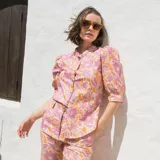 Camisa de lino estampada con flores en tonos rosa y naranja, con cuello mao, mangas cortas abullonadas y cierre frontal con botones.