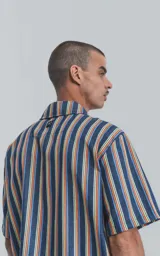Camisa de manga corta con patrón de rayas multicolores, con cierre frontal y cuello tipo camisa.