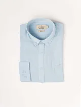 Camisa de manga larga azul, de lino y poliéster, con cuello abotonado y bolsillo en el pecho.