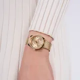 Reloj Guess dorado con caja redonda con strass, esfera dorada con logo de la marca y pulsera de malla milanesa dorada.