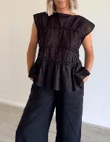 Blusa negra con escote redondo, sin mangas y detalle de frunces horizontales en el frente.