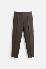 Pantalón de vestir color marrón oscuro, confeccionado en lino italiano. Presenta corte regular fit, cintura con pliegues, bolsillos laterales y traseros ribeteados, y terminación con dobladillo. Cierre frontal con cremallera y botón.