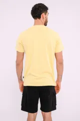 Remera mostaza de algodón con cuello redondo y estampado de una bicicleta con tablas de surf y el texto "Live Simply".
