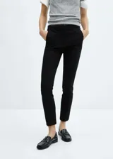 Pantalón crop negro de corte skinny, con tiro medio, trabajillas y dos bolsillos laterales.
