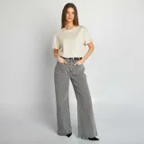 Pantalón de jean gris de corte ancho, con bolsillos delanteros con botón y cinturón negro.