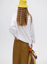 Falda midi de denim color marrón con hilado a la vista en el ruedo y abotonadura frontal.