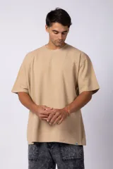 Remera de hombre color crudo, corte oversize, confeccionada en algodón grueso con textura micropanal. Diseño liso sin logos, con costura en forma de 'X' en la espalda. Ideal para un look casual y relajado.