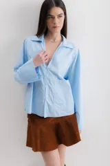 Camisa celeste de algodón con cuello clásico, cierre frontal con botones y bolsillo de parche en el pecho.