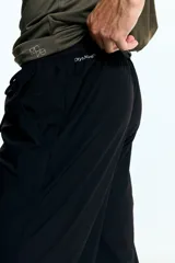 Pantalón deportivo negro de corte ajustado (slim fit) con cintura elástica y cordón de ajuste oculto. Presenta bolsillos al bies y un pequeño logo blanco en la pierna derecha. Confeccionado en tejido funcional DryMove™ con stretch en cuatro direcciones.