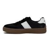Zapatillas urbanas negras con detalle de una franja blanca en el lateral y suela marrón.