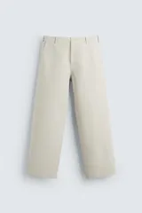 Pantalón color arena de corte amplio, confeccionado en tejido de algodón canvas. Cuenta con pliegues frontales, bolsillos laterales y traseros de doble vivo. Tiene efecto lavado y cierre frontal con cremallera y botón.