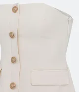 Blusa estilo corset color blanco, con escote recto, sin mangas, abotonado frontal y solapas aplicadas.