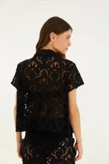 Camisa de encaje negra con botones frontales y mangas cortas.