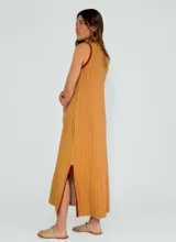 Vestido largo a rayas verticales color gris y blanco, con cuello en V y ribete amarillo. Presenta aberturas laterales con ribete amarillo.