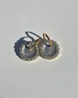 Par de aros colgantes con dije circular de resina con glitter multicolor y borde de strass. El arito es de acero quirúrgico dorado.